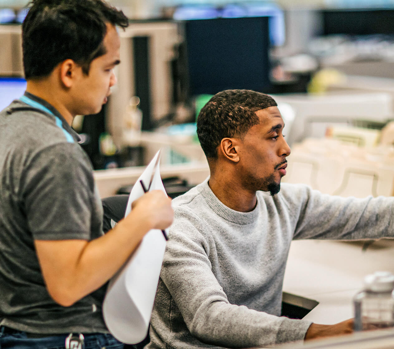 Two Henderson Engineers employees working together on a project in a cubicle.