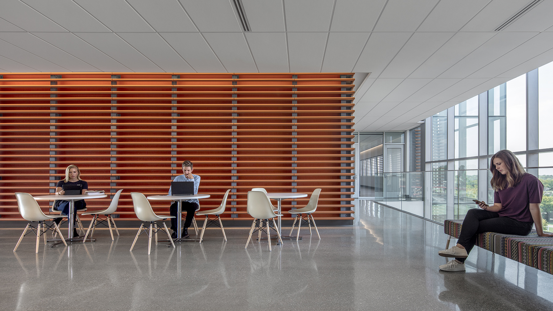 Interior of a college welcome center lobby with students sitting at tables and chairs.